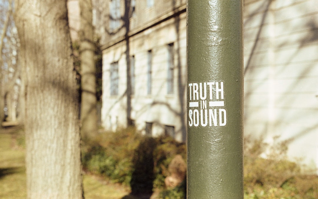 a green pole with a sticker on it in front of a building